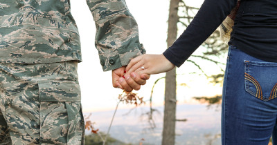 man in military uniform holding a woman's hand