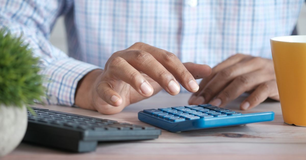 A close-up of a person typing on a calculator. 