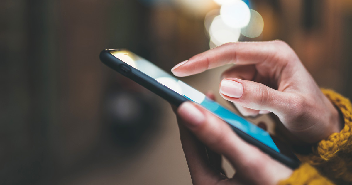 A closeup of hands holding and using a cell phone 