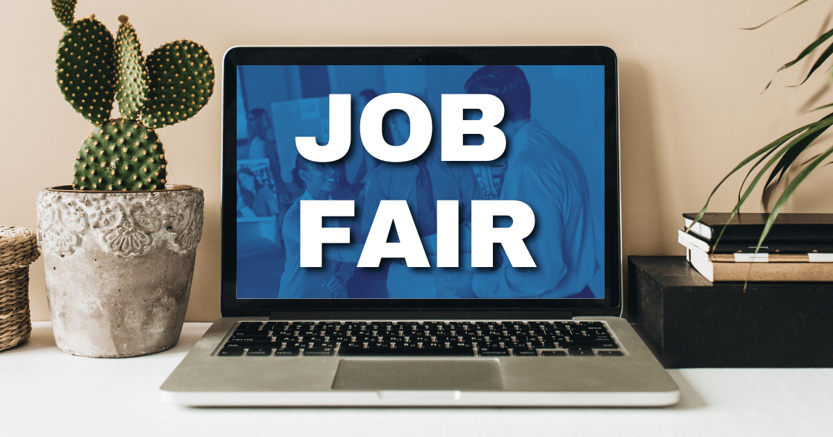 A laptop with the text “Job Fair” on the screen in white letters. To the left of the laptop is a cactus, to the right of the laptop is a stack of notebooks. All items are sitting on a desk. 