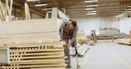 A construction worker, who has a prosthetic leg, is examining wood planks.